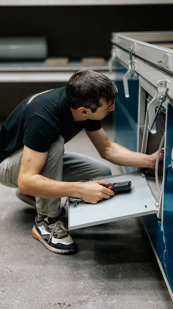 A focused technician inspects machinery indoors, ensuring operational efficiency.